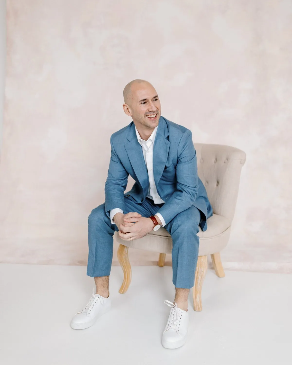 Matthew Roberts laughing, seated in a light blue suit