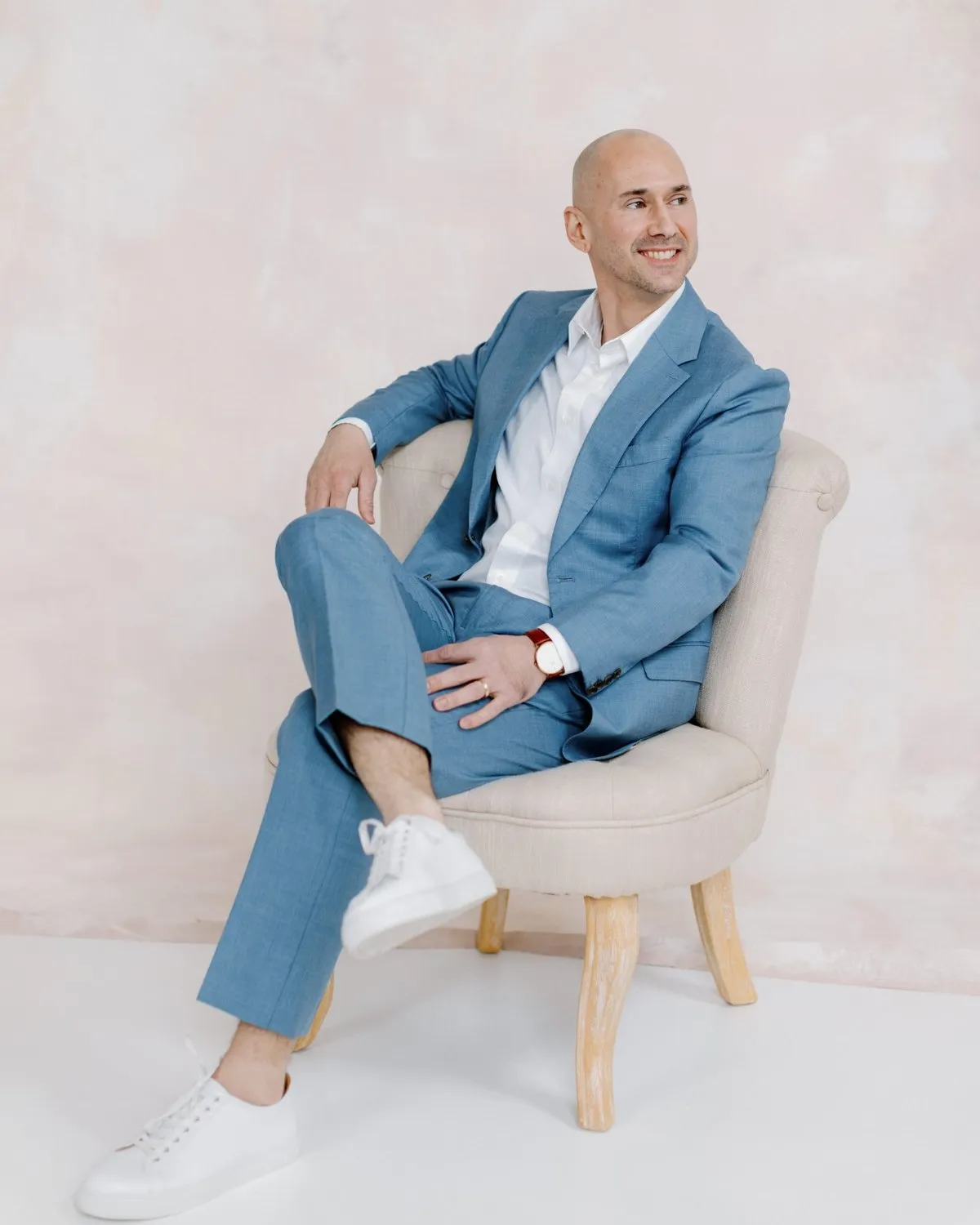 Matthew Roberts smiling, seated in a light blue suit